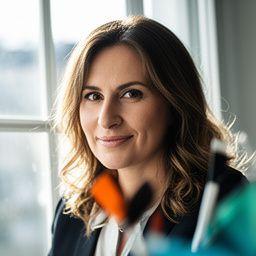 Lea Vidmar am Studiofenster mit Tintenschale und einem konzentrierten, freundlichen Ausdruck